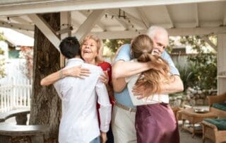 Multi-generational family sharing warm hugs outdoors under a pergola, representing hope and reconnection during early addiction recovery.